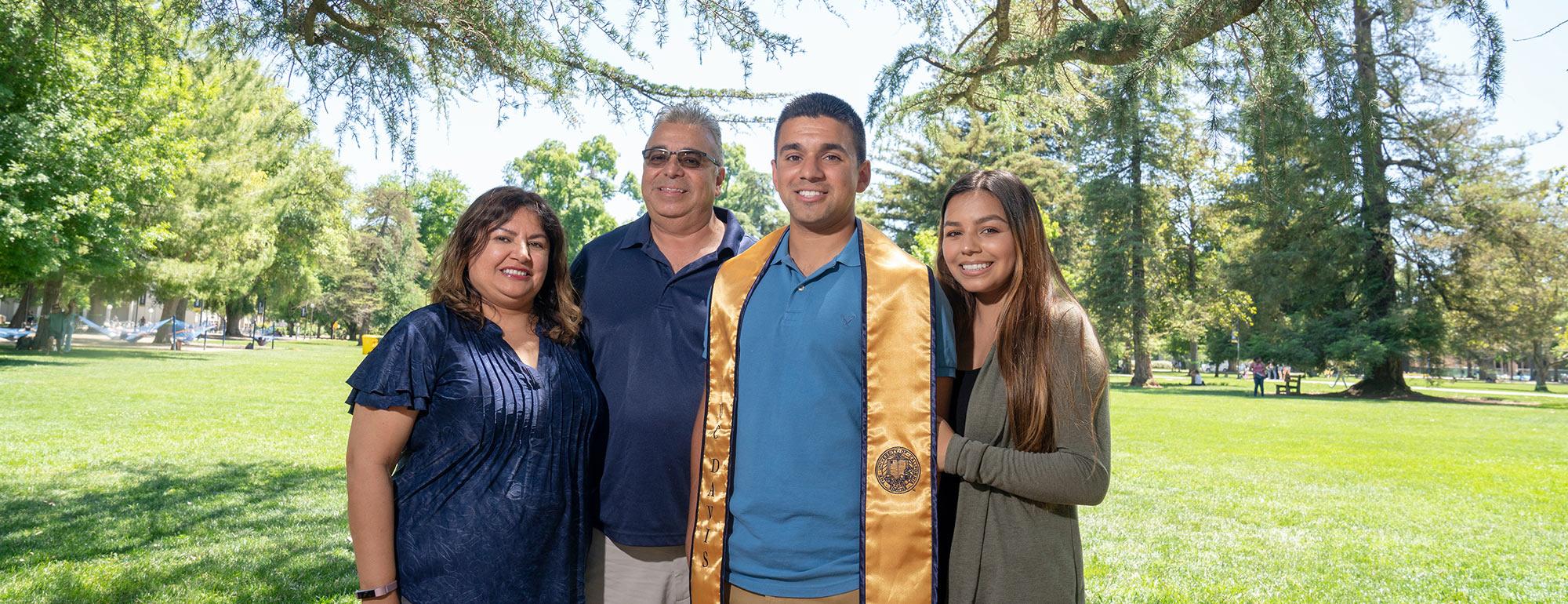 Parents pose with their TV graduate son on the quad 