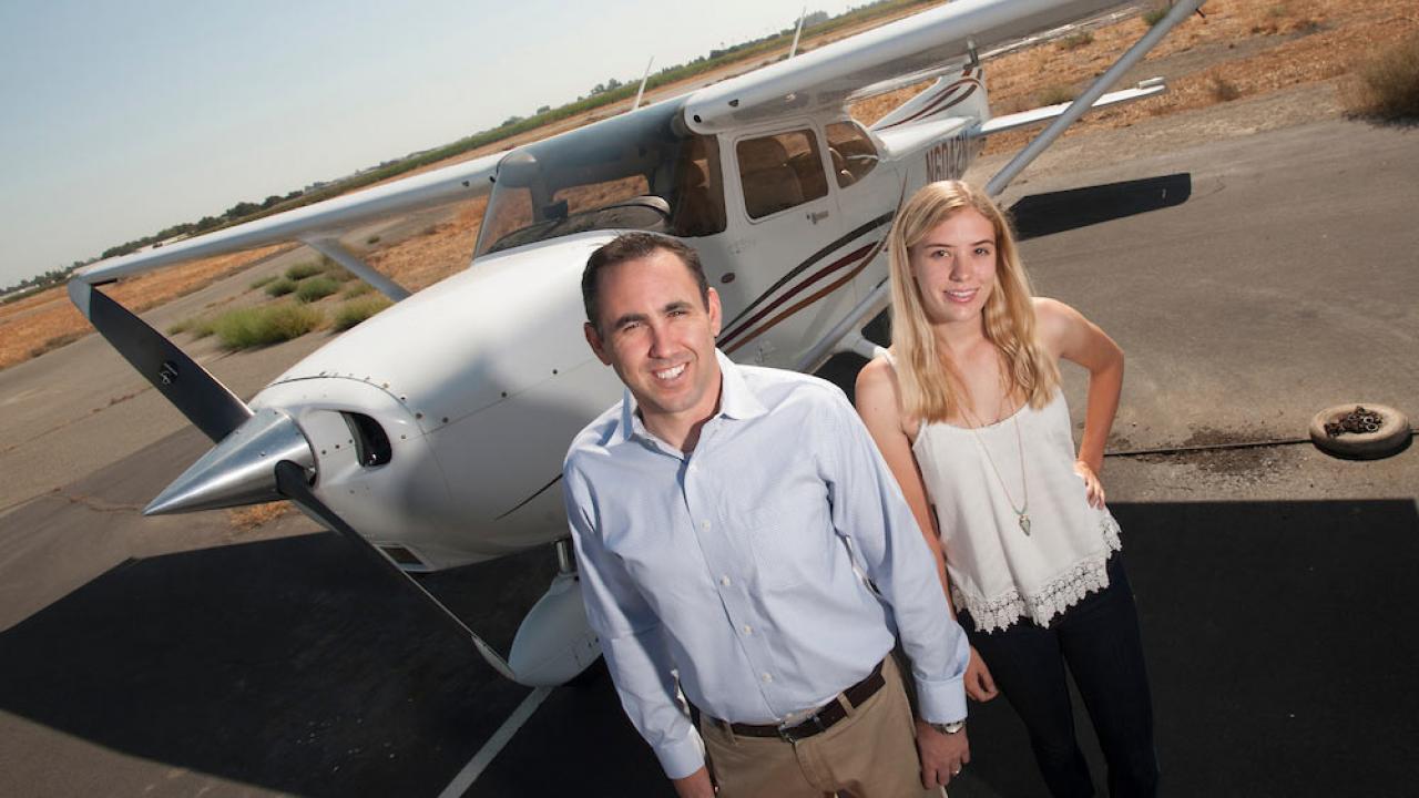 An instructor and student pose for a shot in front of an airplane at TV airport