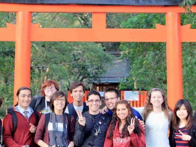 TV students pose in front of a shinto shrine in japan.