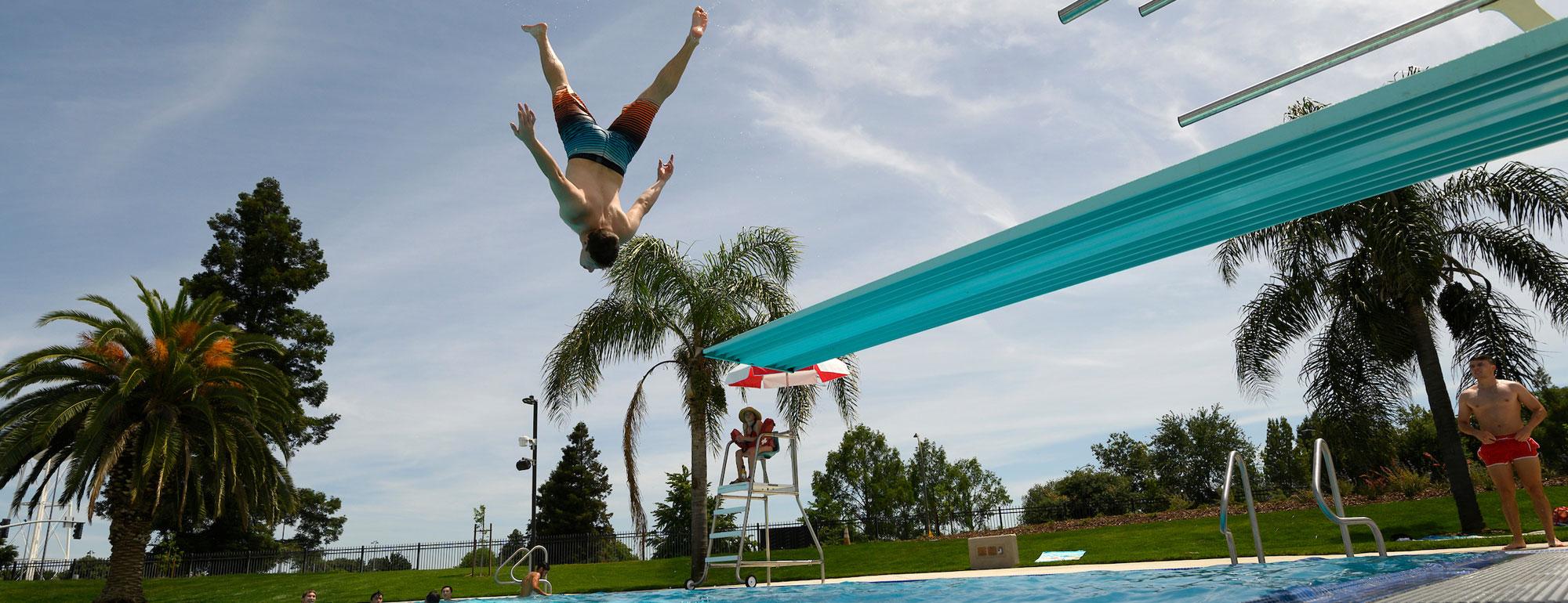 A student doing an acrobatic jump of of the diving board at the TV Recreation Pool